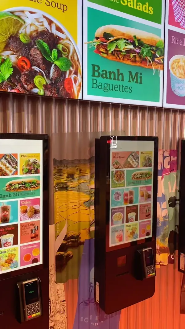 The video showcases Hop Vietnamese Street Food, a new eatery located in Bond Street Tube Station. It highlights various dishes, including HOP boxes (customizable rice bowls), noodle salads, Banh Mi baguettes, and kids' meals.  The video shows close-ups of food items, showcasing textures and vibrant colors. Dietary information, such as vegan options (marked with (VE)), is subtly displayed. The video focuses primarily on showcasing the food and the restaurant's ambiance.