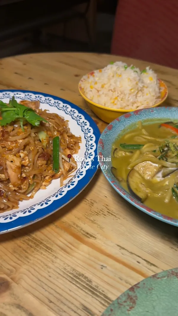 The video showcases a meal at Rosa's Thai restaurant in White City, London.  It features various dishes, including drinks with popping boba, prawn crackers with a sauce, spring rolls, chicken satay with peanut sauce and toasted bread, Pad Thai, green curry, and egg fried rice.  For dessert, there's a brownie with ice cream and sauce. The video emphasizes the visual appeal of the food and the pleasant atmosphere of the restaurant.