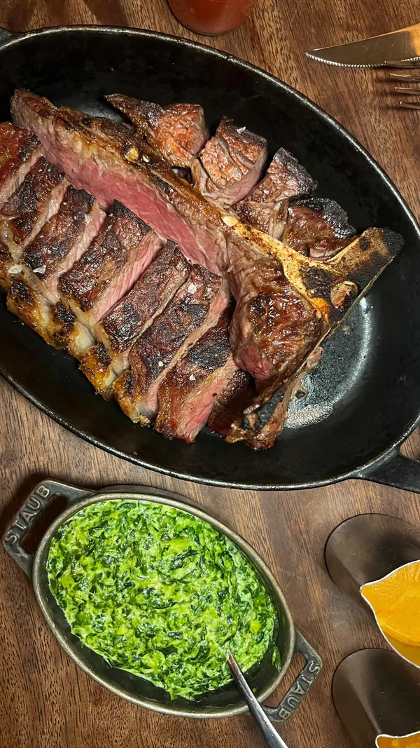 This video showcases a meal at the Hawksmoor Seven Dials restaurant near Covent Garden.  The video highlights various dishes including bone marrow and onions, roasted scallops, a T-bone steak, creamed spinach, and two desserts.  The cocktails Pink Gibson and Double Melon Daiquiri are also featured. The presentation focuses on close-ups of the food and drinks, with some shots of the restaurant's ambiance. Dietary information is not explicitly stated.