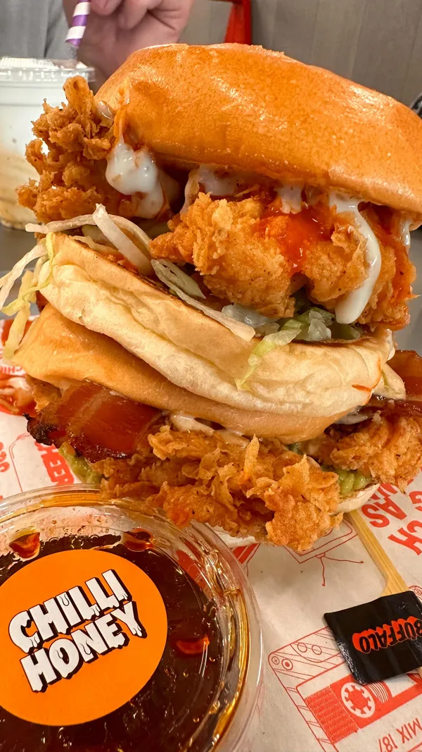 The video showcases a visit to Butchies, a fried chicken restaurant in Ealing, London. The content focuses on two chicken burgers (the Buffalo and the Jenny from the Block), hot shake fries, and milkshakes.  The food is presented in detail, emphasizing textures and colors. Various sauces are shown being used to enhance the flavor profiles, and the overall feel is energetic and upbeat. No specific dietary information is provided.
