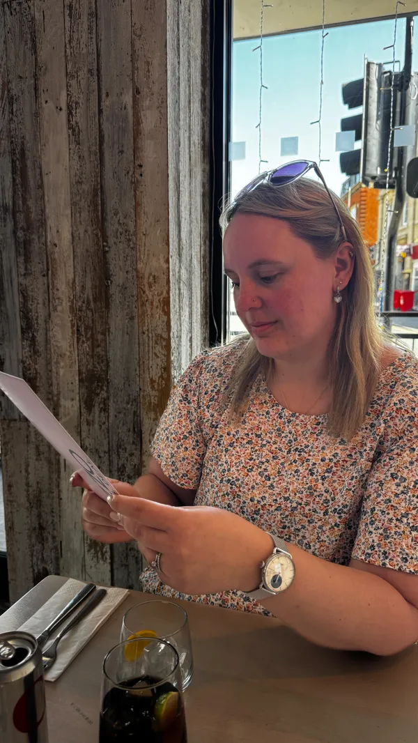The video features a woman eating bruschetta at a Prezzo restaurant. It shows the exterior of the restaurant, the interior dining area, and a brief interaction with a server. The video displays the Prezzo lunch menu, highlighting the soup & panini and two-course options. It includes shots of two pasta dishes (Rigatoni Bolognese and Rigatoni Carbonara) and a drink being poured. The video concludes with the woman holding the menu and a close-up of the bill, showing a '100% Free Lunch' discount applied.