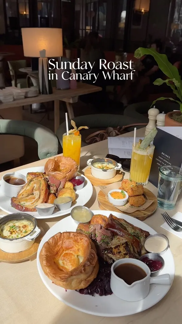The video showcases a Sunday roast meal at No. 35 Mackenzie Walk in Canary Wharf, London. It highlights the restaurant's ambiance, waterside location, and the delicious roast dinner, including roast meats, Yorkshire puddings, roasted potatoes, gravy, and various side dishes. Two cocktails are also featured. The presentation emphasizes abundant portions and a sunny atmosphere. No dietary information is explicitly provided.