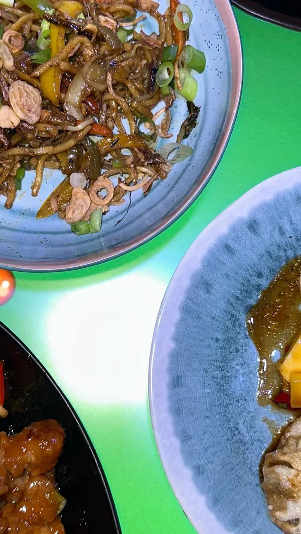 The video showcases Inamo restaurant in Covent Garden, focusing on their bottomless sushi and Asian tapas deal. It features various dishes including sushi rolls with tuna topping, noodles, and sweet and sour chicken. The presentation is simple, with food displayed on plates against various backgrounds. No specific dietary information is provided. The video primarily focuses on showcasing the food and promoting the restaurant's bottomless deal.