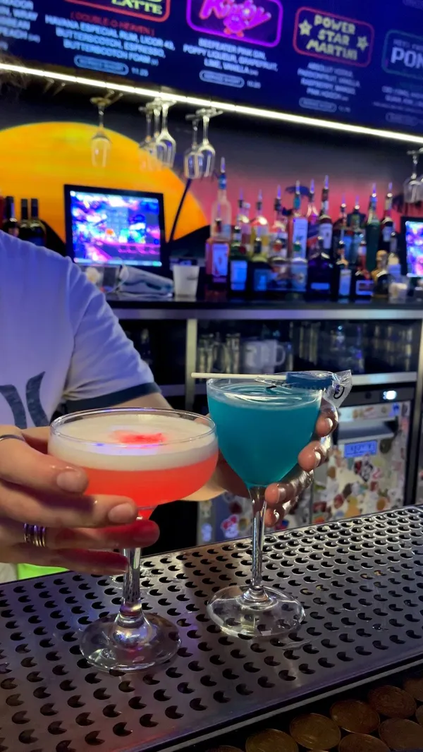 The video showcases a date night at NQ64, an arcade bar in Soho, London. It highlights the bar's atmosphere, cocktail menu (including the "Power Star Martini" and a blue cocktail), and various arcade games available, such as Pac-Man, Mario Kart, and The House of the Dead.  The video also shows the process of making cocktails at the bar and customers enjoying the games. The primary focus is on the overall experience of the arcade bar, combining drinks and classic arcade games.