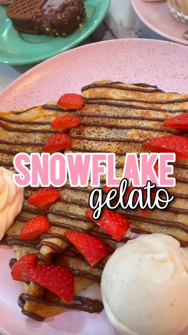 The video showcases Snowflake Gelato, a cafe located in Soho, London. It features various menu items such as the Lotus Biscoff milkshake, Lotus Biscoff milk cake, a Nutella crepe with strawberries, and a gelato cookie. The cafe's pink interior and decor are prominently displayed. The main focus is a meal showcase, highlighting the food and the cafe's atmosphere.