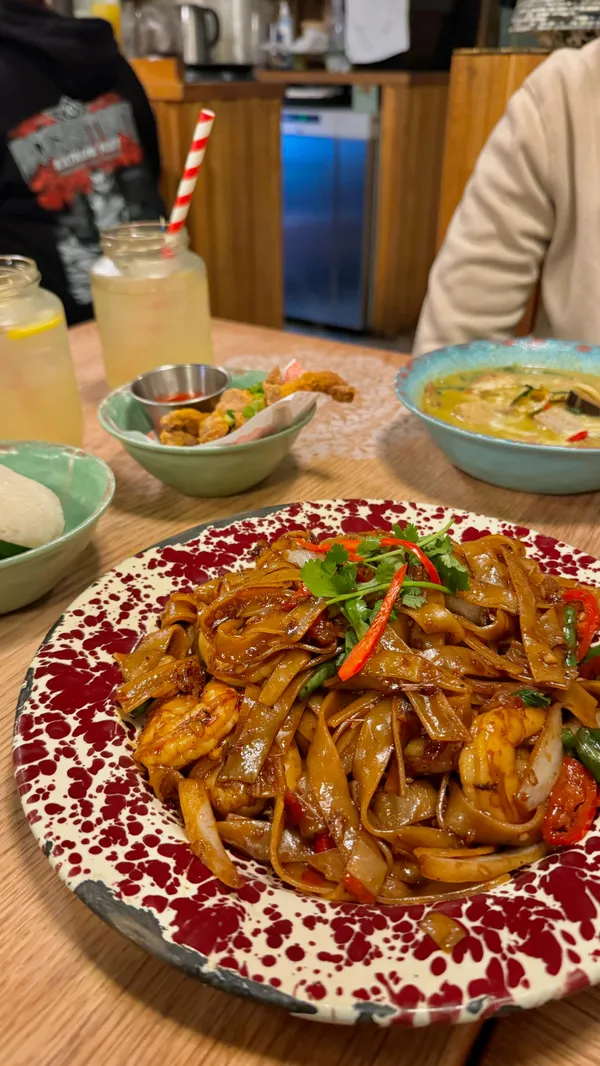 The video showcases a meal at Rosa's Thai restaurant in London.  It features various dishes including prawn crackers, crispy pork bites, green Thai curry, drunken noodles with prawns, and homemade lemon iced tea. The food is presented in rustic-style plates and bowls, with vibrant colors and close-up shots highlighting the textures and ingredients.  The video emphasizes the spiciness of the green curry. No specific dietary information is provided.