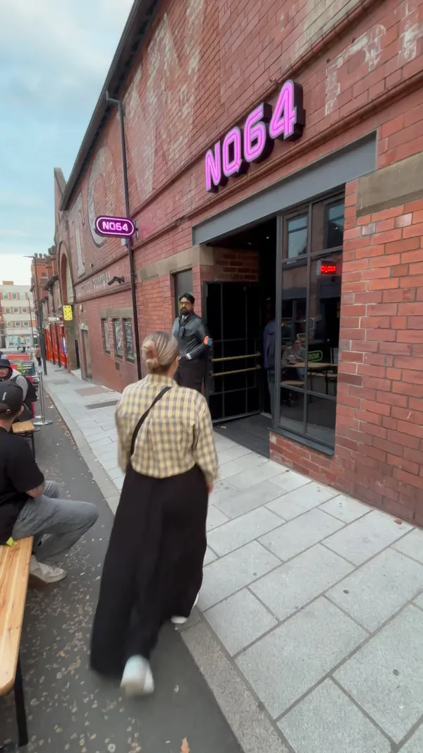 The video showcases NQ64, a gaming bar in Leeds, UK. It highlights various aspects of the bar, including its extensive drink menu (cocktails, beers), arcade games (Pac-Man, Tetris, Dance Dance Revolution), console games (Game Boy, various consoles), and a photo booth. The overall atmosphere is vibrant and nostalgic, with neon lighting and retro decor.  Drinks are shown, including cocktails and beers on tap. No specific dietary information is provided.