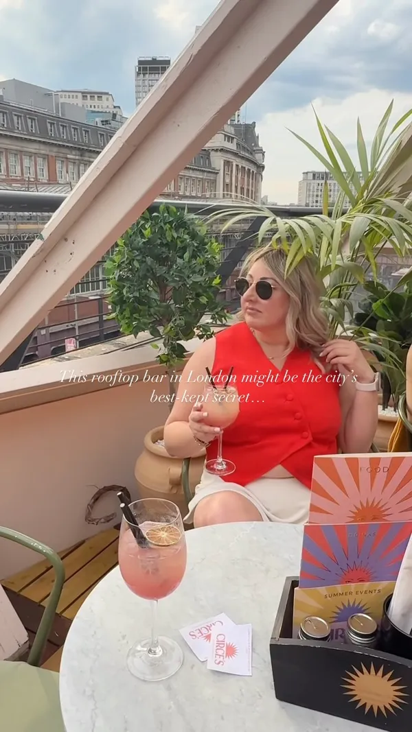 Video showcases a rooftop bar in London with views of the city, including The Shard. It features various seating areas, small food bites served on platters, and cocktails being prepared and enjoyed by patrons. The bar area with a selection of bottles is also shown.