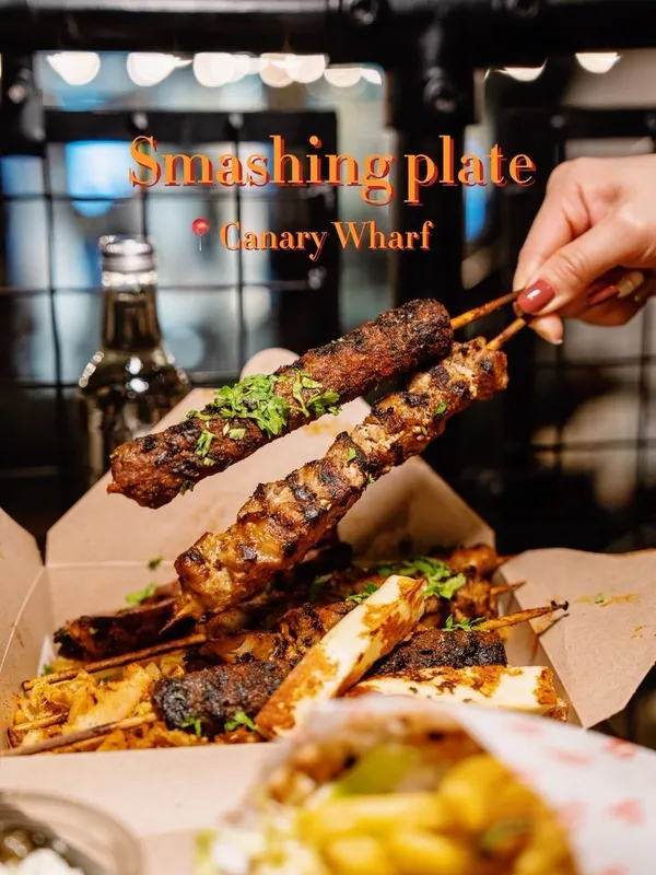 The video showcases a meal from Smashing Plates, a Greek takeaway restaurant in Canary Wharf, London.  It features a variety of dishes, including a grilled feast with skewers of meat and halloumi, a chicken souvlaki wrap, halloumi fries, a Greek salad, and a chocolate brownie. The food is presented in takeaway boxes and containers. The video is primarily a food showcase, highlighting the quantity and visual appeal of the dishes. No specific dietary information is provided.