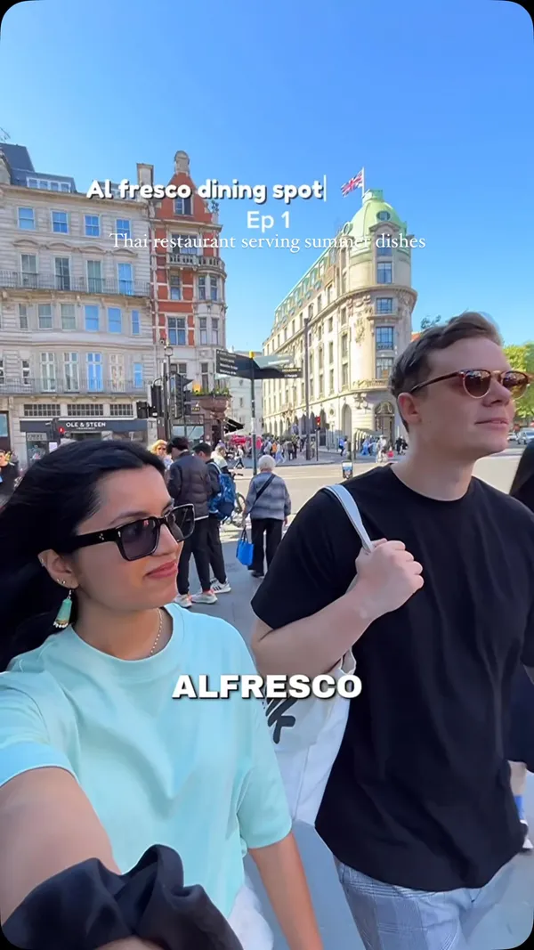 A couple visits Rosa's Thai restaurant in London to try their new summer dishes. The video shows them walking to the restaurant, trying Kale Tempura, Thai Spiced Pork Ribs, and Minced Chicken Salad (Larb Gai), and drinking Thai Iced Tea. It features close-ups of the food, shots of the couple eating, the drinks, and views of the restaurant's outdoor and indoor seating areas.