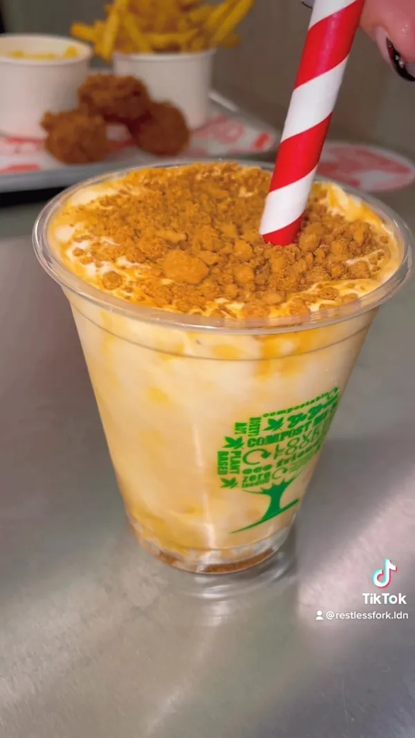 The video showcases Butchies Fried Chicken restaurant in London, highlighting their festive menu.  It features close-ups of their Sweet Baby Cheesus burger (deep-fried camembert with cranberry sauce and chilli honey), halloumi fries, chicken strips, and a Biscoff milkshake. The food is presented attractively on trays and plates, emphasizing its visual appeal.  No specific dietary information is provided. The video primarily focuses on showcasing the food and drink items.