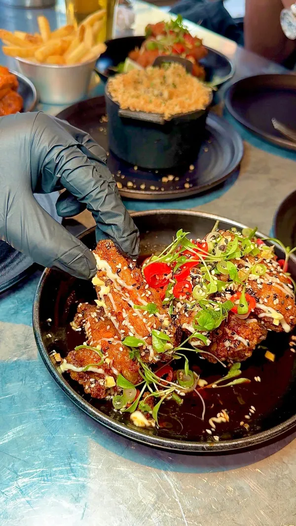 This video showcases Wingmans' Express Lunch menu (£12), featuring various chicken wings (Buffalo, Shanghai Oriental, Jamaica Me Crazy), a classic burger, truffle mac & cheese with slow-cooked beef, rosemary fries, and a royal cookie crumble dessert.  The video is shot in the restaurant and kitchen settings, emphasizing the food's preparation and presentation.  The food is presented attractively, highlighting colours, textures and layers.