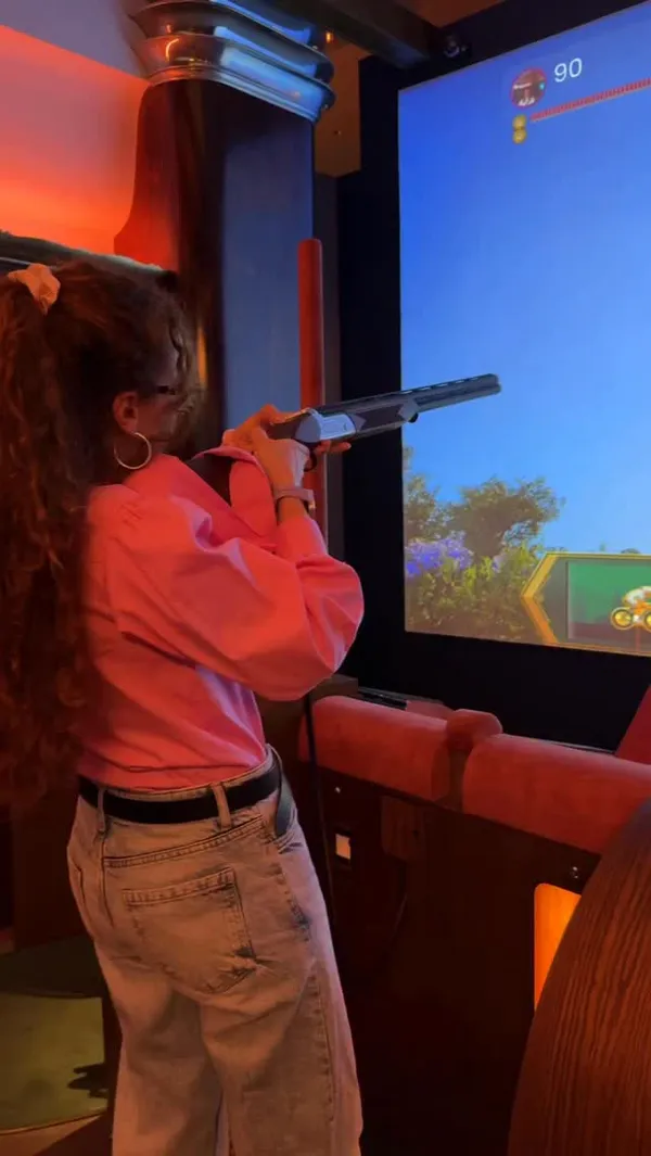 A short, energetic vlog showcasing a visit to Clays Soho, a venue that combines digital clay pigeon shooting with a cocktail bar. The video features the creator participating in the shooting game, enjoying cocktails, and using the venue's photo booth, highlighting the fun, competitive atmosphere.