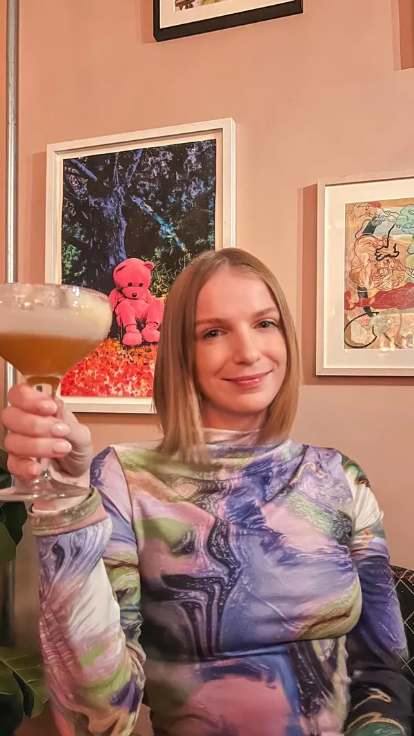 This video showcases The Little Scarlet Door, a London bar. It features various cocktails (including an orange-colored one, and a taller drink with cucumber), the bar's interior (with a pink theme, shelves, and lighting), and snippets of the bar's downstairs dance floor. The video emphasizes the bar's atmosphere and nightlife experience.