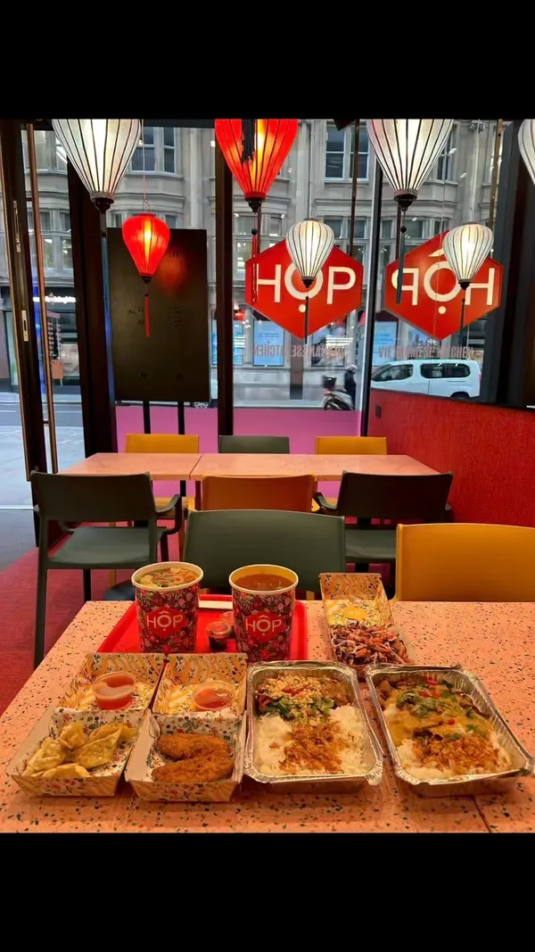 The video showcases HỐP, a Vietnamese restaurant in London's city area.  The influencer orders food via a tablet, collects it, and then shows various dishes, including pho (both pork and vegetable options), HOP boxes with lemongrass pork and miso sweet potato satay, prawn dumplings, and VFC dippers. The food is presented in visually appealing containers and packaging.  The video emphasizes the quick service and overall restaurant experience.
