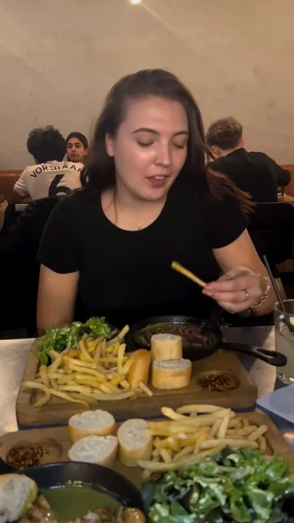 The video showcases a meal from Swiss Butter in Holborn, London. It features grilled sliced steak in a green sauce, served with french fries, a side salad with yellow dressing, and slices of baguette.  Two desserts are also presented: a molten chocolate cake and a pain perdu. The main focus is on the food presentation and the influencer's positive experience.