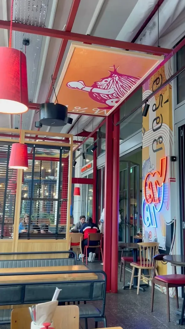 This video showcases a meal at Rosa's Thai restaurant in Westfield White City, London. The video starts with shots of the restaurant's interior and menu.  The main focus is on a selection of Thai dishes ordered from the £12 lunch menu, including prawn crackers with peanut sauce, chicken red curry with rice, chicken pad khing ginger stir-fry, gai satay (grilled chicken skewers), egg fried rice, roti bread, and stir-fried broccoli. The presentation includes close-ups of the food and overhead shots of the table setting. No dietary information is explicitly mentioned.