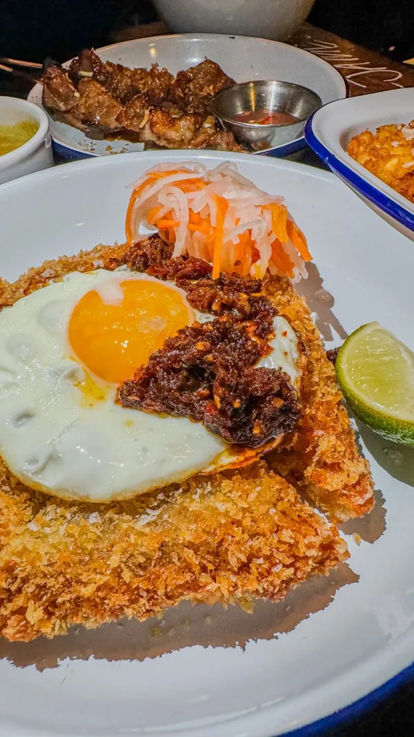 The video showcases Mamapen, a Cambodian pop-up restaurant at King & Co.  It features various dishes: hash browns with sour curry sauce, BBQ pork neck skewers, panko pork toast with a fried egg, tattie mince noodles (braised beef mince noodles with cucumber, spring onion, and chili), and mango and coconut sponge cake. The food is presented in a visually appealing way, with close-up shots highlighting textures and colors. Dietary information is provided for vegetarian (VE) options. The main focus is on promoting Mamapen's Cambodian cuisine.