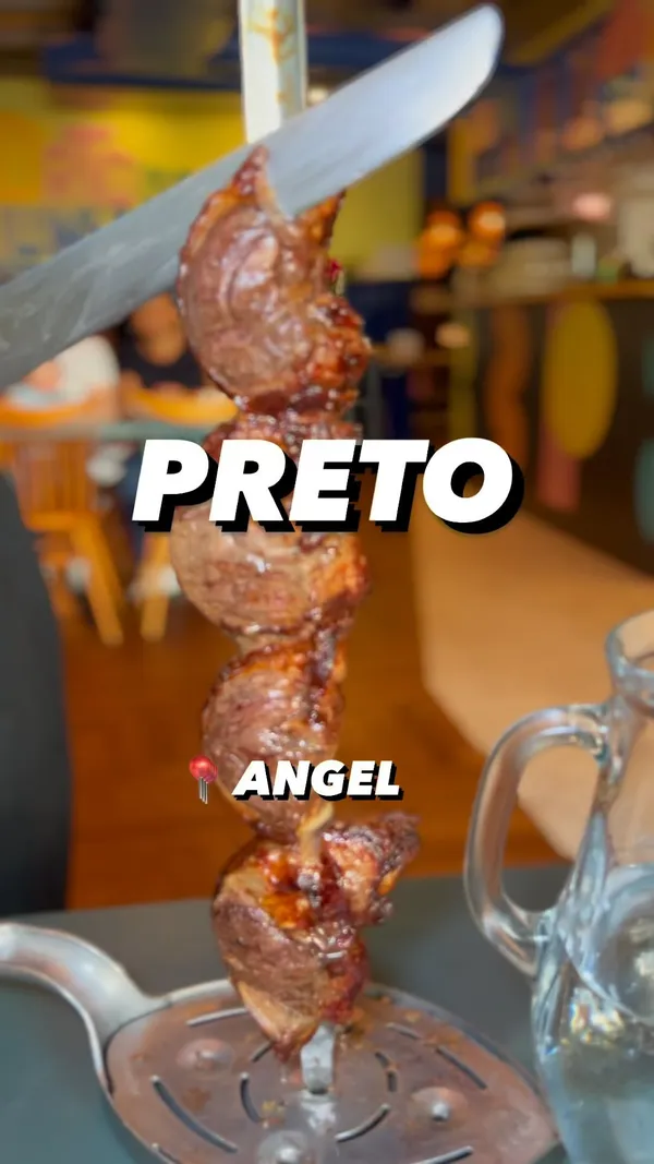 This video showcases Preto, a Brazilian steakhouse in Angel, North London. It features various food items including unlimited meats (beef, chicken), a salad bar with options like leaf salad, sweetcorn, beetroot and orange salad, pasta salad, and other sides such as rice and various sauces and dips. Bread rolls are also presented. The meat is presented on skewers, carved and served tableside. Dietary information mentions Halal options. The primary focus is on the all-you-can-eat Brazilian steakhouse experience, highlighting the food and the dining atmosphere.