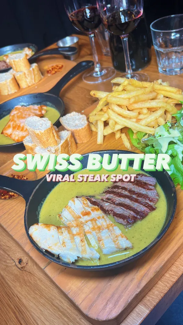 This video showcases Swiss Butter restaurant in London. It highlights a steak board with a unique butter sauce, along with sides like fries, salad, and bread. The desserts shown are a chocolate lava cake and a dessert resembling a creme brûlée. The video is primarily focused on showcasing the food and restaurant ambience.