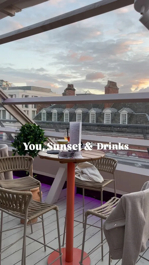 The video showcases a rooftop bar in London, offering a stunning sunset view. Two cocktails are prominently displayed on a table, along with a menu. The drinks are presented in elegant glassware. No dietary information is provided. The main focus is the ambiance and atmosphere of the bar, highlighting the view and the drinks.