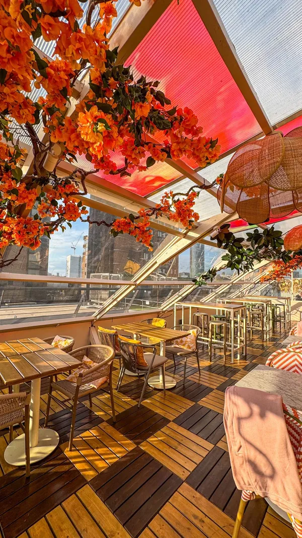 The video showcases Circe's rooftop bar in London. It starts with a view of the entrance mural, then moves upstairs to show the rooftop setting with seating, decor, and views. It features various cocktails (Kiwi Margarita, Pornstar Martini, Cocoa Nero Negroni, Peach Gimlet) and Mediterranean-inspired small plates (Spiced Lamb Kofta Skewers, Tiger Prawns, Grilled Broccoli, Baba Ganoush, Buffalo Mozzarella with Courgette, Fried Halloumi). The focus is on the summery ambiance, drinks, and food offerings. A text overlay encourages viewers to visit during a heatwave.