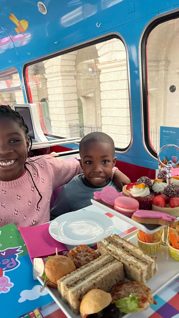 The video showcases a Peppa Pig-themed afternoon tea experience on a double-decker bus tour in London.  It features various sweet and savory treats, including macarons, cupcakes, sandwiches, and fruit tarts.  The food is presented on tiered stands and individual plates. Children are shown enjoying the food, singing songs, playing games, and looking at the sights of London through the bus windows.  No specific dietary information is provided.