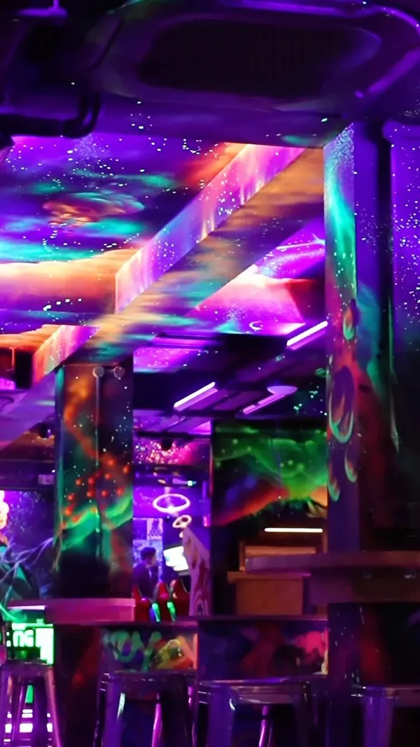The video showcases NQ64 Cardiff, a retro arcade bar. It features various arcade games like Mario Kart, Pac-Man, and Street Fighter II, along with console games on Super Nintendo and Xbox. The video also shows bartenders preparing drinks in a neon-lit environment.  No specific food or drinks are highlighted, the focus is on the atmosphere and gaming experience.