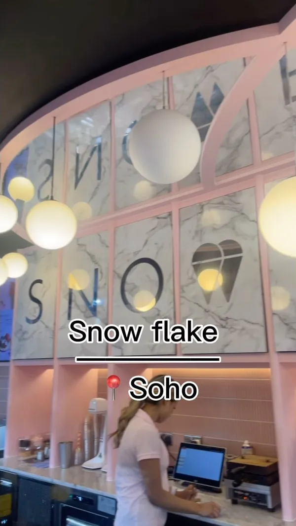 The video showcases Snowflake Gelato in Soho, London. It features various desserts, including a limited-edition Wimbledon Tennis Ball dessert (a creamy sphere with strawberry compote), crepes with chocolate and ice cream, and a tiramisu-like dessert.  The presentation focuses on pastel pink plates and a clean, modern aesthetic.  No specific dietary information is provided. The main focus is showcasing the desserts and the cafe's ambiance.