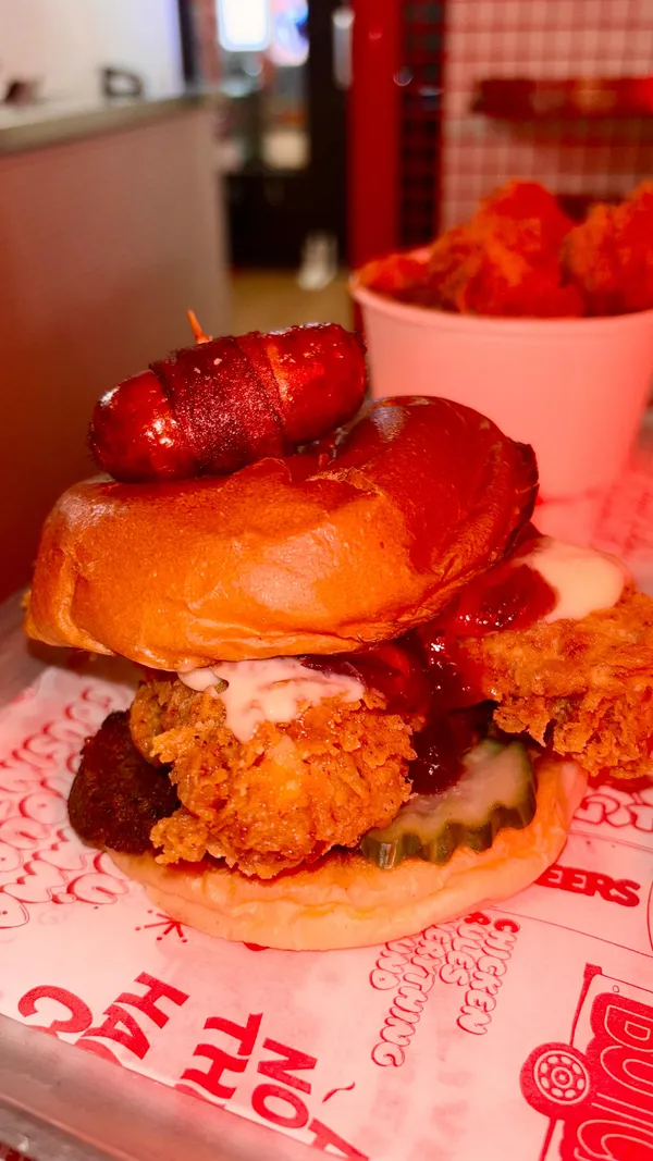 The video showcases Butchies' Christmas menu in London, highlighting their Baby Cheesus Blanket Burger (camembert cheese, pickles, stuffing, cranberry sauce, chicken in a blanket), popcorn chicken with gravy, spicy fries with chilli honey, and mac and cheese.  The setting is the restaurant itself, with close-ups and shots showing the food being prepared and served.