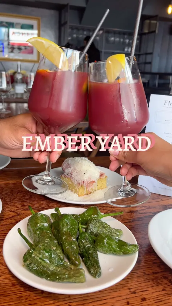 The video showcases a brunch tapas menu at Ember Yard restaurant.  It features various tapas dishes, including Padron peppers, focaccia with mortadella and manchego, pan-fried prawns with croquettes, chorizo with pineapple and jalapeno, burrata with pea pesto, and tortilla. The drinks shown are sangria. The video intersperses shots of the food with shots of the restaurant's ambience and the couple enjoying their meal. 