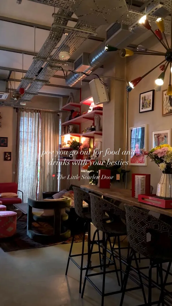 The video showcases Little Scarlet Door, a bar in London's Soho. It features various cocktails (including a large punch bowl), bar snacks (like hummus with pita bread), and friends playing a board game. The setting is dimly lit with a retro aesthetic. Drinks are presented in glasses and the punch bowl is in a disco ball. The video focuses on a fun night out with friends at the bar.