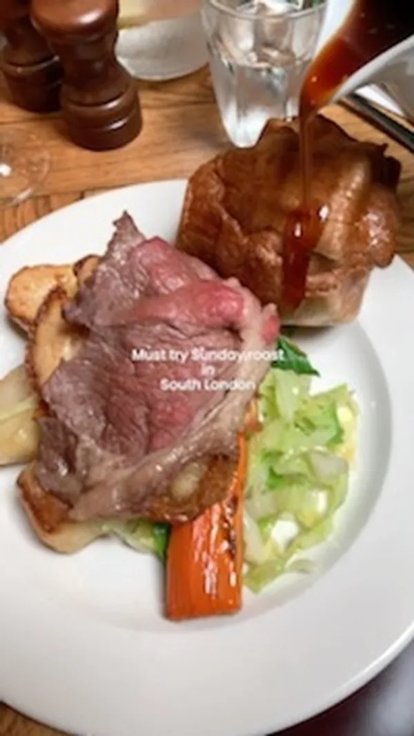 The video showcases a Sunday roast at The Cyclist pub in Balham, South London.  It features various dishes including roast beef, roast chicken, pork belly, Yorkshire pudding, roast potatoes, cauliflower cheese, and gravy.  The food is presented on white plates, with close-ups highlighting textures and colors.  The video doesn't explicitly mention dietary options. The main focus is on the visual appeal and deliciousness of the Sunday roast.