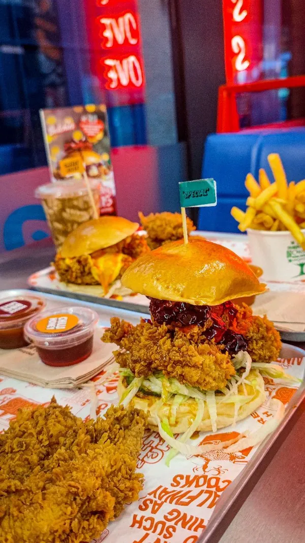 The video showcases Butchies, a fried chicken restaurant in Ealing, London. It features various menu items, including two burger options (Sweet Baby Cheesus and Cheesy Rider), sides like fries, halloumi fries, hot wings, and chicken tenders, and two milkshake options (Biscoff chocolate and Oreo vanilla). The food is presented in close-up shots, highlighting textures and colors, with a focus on the richness and appealing visual aspects.  Halal status is mentioned. The video's main focus is a meal showcase.