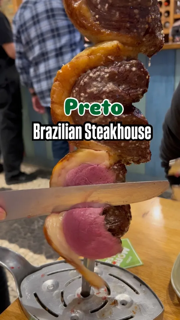 Video showcasing a Brazilian steakhouse (churrascaria) experience. Features various cuts of meat being carved tableside directly from skewers, including close-ups of the meat's doneness. Also shows the preparation and consumption of a passion fruit caipirinha cocktail. Includes shots of a buffet/salad bar with various options like salads, pasta salad, corn, chickpea salad, and a stew. Ends with shots of desserts, including flan and a passion fruit dessert.