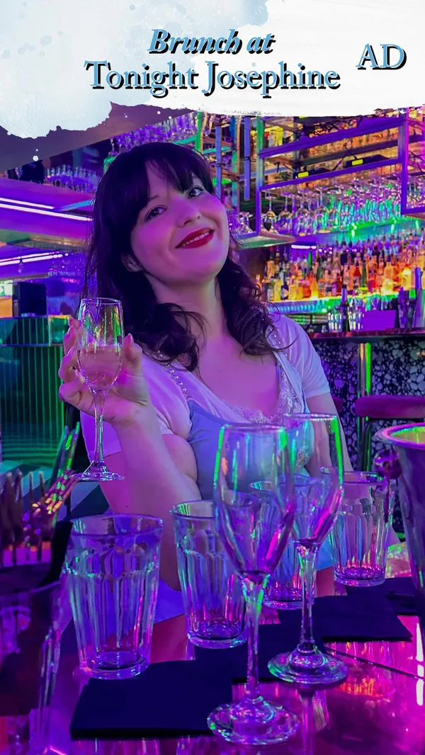 The video showcases Tonight Josephine, a bar in London, promoting their upcoming burlesque, bad girl, and pop icons brunches. It features various shots of food (pulled pork burger, buttermilk chicken burger, loaded nachos, waffles), cocktails, and drag queens performing. The overall atmosphere is vibrant and energetic, with purple and green lighting dominating the setting.