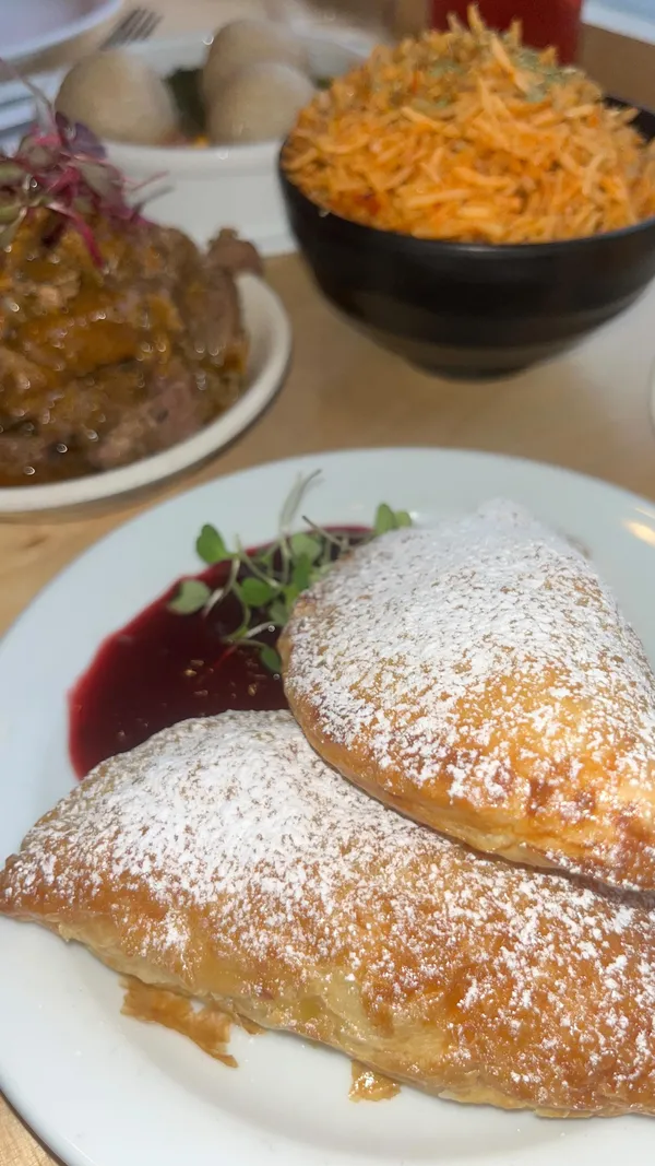 The video showcases a meal at Chuku's, a Nigerian tapas restaurant. It features various dishes, including smoked turkey meat pie, jollof rice, egusi bowl, banga prawns, lamb ayamas, caramel kuli kuli wings, and puff puff rum baba.  A cocktail called Okiki is also shown. The food is presented in close-up shots, highlighting textures and colors. No specific dietary information is provided.