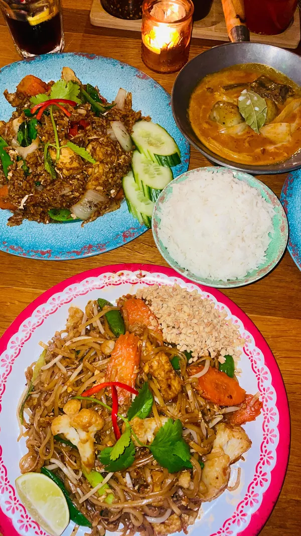 The video showcases a meal at Rosa's Thai restaurant in Angel, London.  It features a mixed vegetable starter platter (summer rolls, sweetcorn fritters, okra tempura, veggie spring rolls, pumpkin crackers), tofu Pad Thai, vegetable and tofu Khao Pad, and Massaman beef curry. The food is presented on colorful plates, with close-up shots highlighting textures and details.  Vegetarian/vegan options are evident. The main focus is on the food and the restaurant's atmosphere.