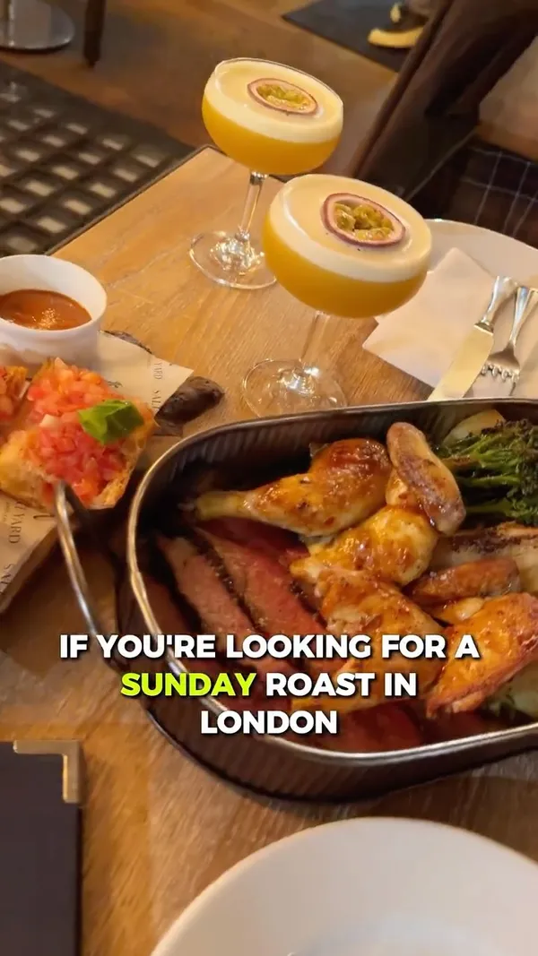 The video showcases a Spanish-style Sunday roast at the Salt Yard Borough restaurant in London. The meal is served family-style and features charcoal-cooked meats, including 35-day aged sirloin and corn-fed baby chicken. Various side dishes are shown, such as pan con tomate, tomato salad, and fresh greens. The video also highlights passionfruit cocktails and the restaurant's warm, industrial-chic interior.