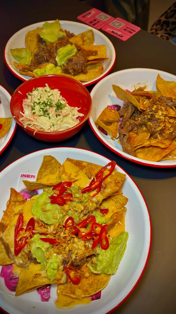 The video promotes TOCA Social, an indoor football-themed entertainment venue. It showcases various interactive football games being played by groups of friends in private booths. The video also highlights the food and drink offerings, including cocktails, loaded nachos, a chicken and bacon burger, and various sides like sweet potato fries, crinkle-cut fries, and broccolini. The overall atmosphere is portrayed as fun, social, and energetic, suitable for a group night out.