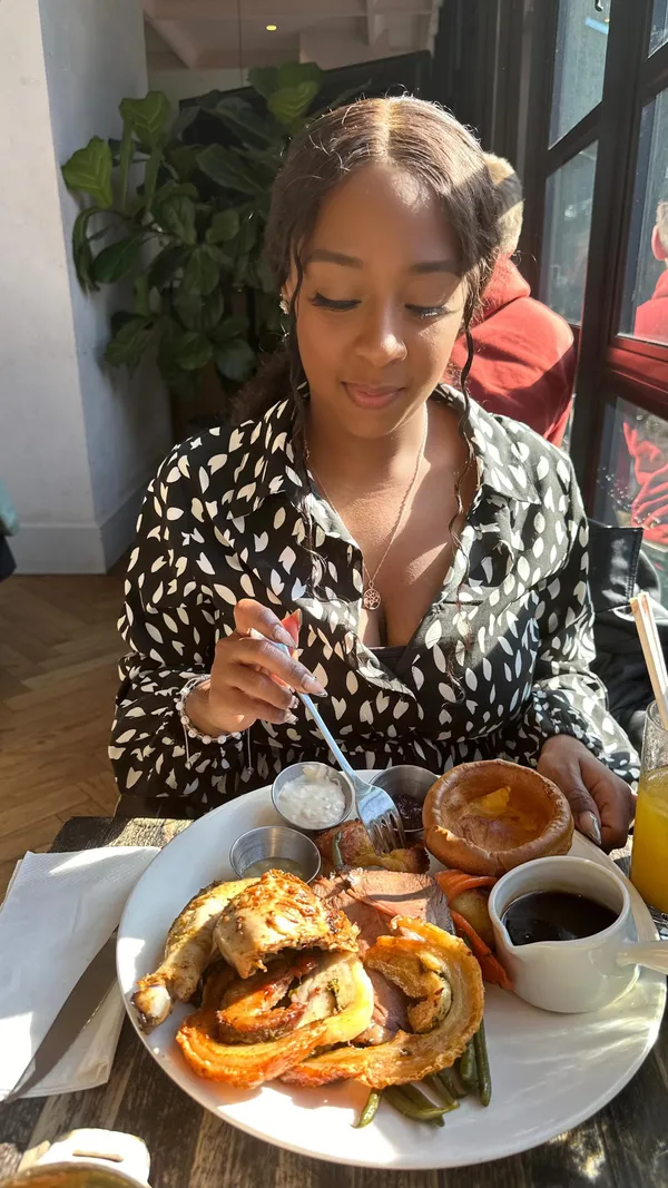 This video showcases a Sunday roast at No.29 Powerstation West in Battersea. It features various dishes, including calamari, roast pork, beef, and chicken, along with Yorkshire puddings, roasted vegetables, and gravy.  The dessert shown is a raspberry and apple crumble. The video emphasizes the deliciousness of the food, the generous portions, and the free refills of gravy. The atmosphere is bright and sunny.