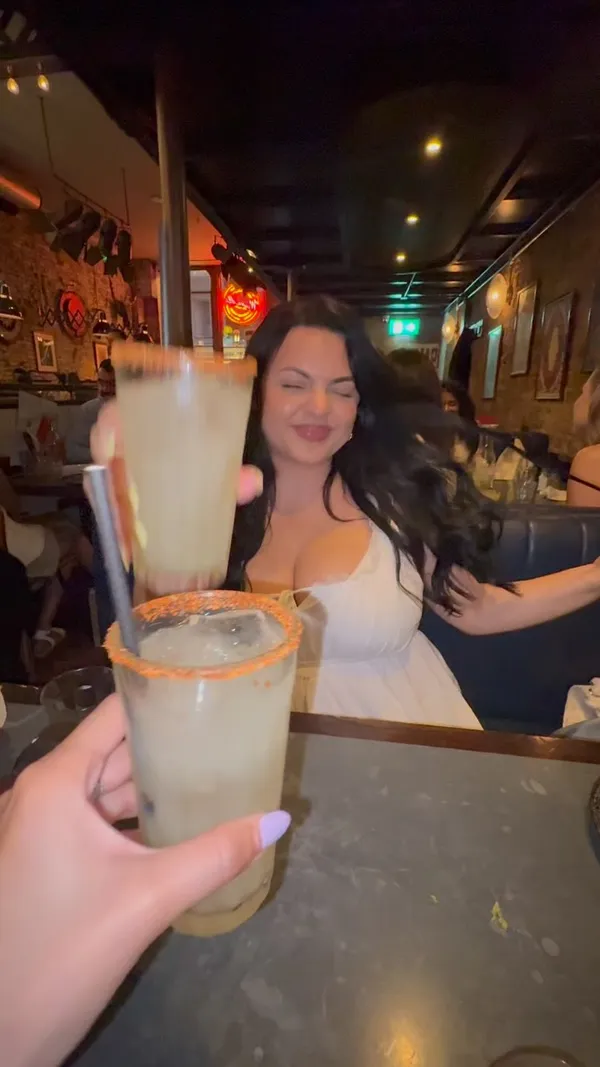 The video features two women dining at The Taco Social Club in Covent Garden. It showcases margaritas, a close-up of a taco, the cocktail menu, a large plate of nachos, and various tacos served on wooden stands. The creator provides a voiceover review, highlighting the cocktails and nachos, and mentioning a bottomless margarita deal.