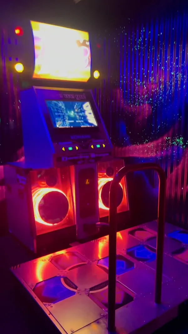 The video showcases NQ64, an arcade bar in Leeds, UK. It features the bar's neon-lit exterior and interior, highlighting the cocktail-making process of a 'Quick Revive No.5' and various arcade games, including racing and dance games. The overall atmosphere is energetic and vibrant, focused on the gaming and social aspects of the bar. No specific dietary information is provided.