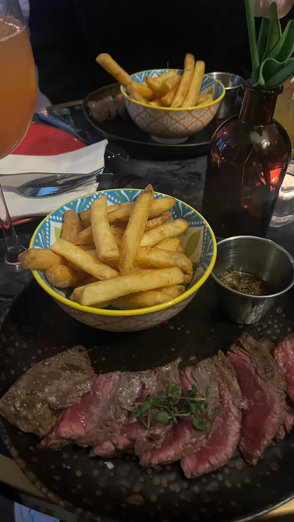This video showcases a visit to The Little Blue Door Fulham restaurant. It features various dishes, including halloumi fries with a berry sauce, sea bass tacos with guacamole and a creamy sauce, and steak with chips.  The cocktails shown are a margarita-style drink and a larger cocktail garnished with a toasted marshmallow. The video emphasizes the food and drink, the restaurant's ambiance, and the overall experience.