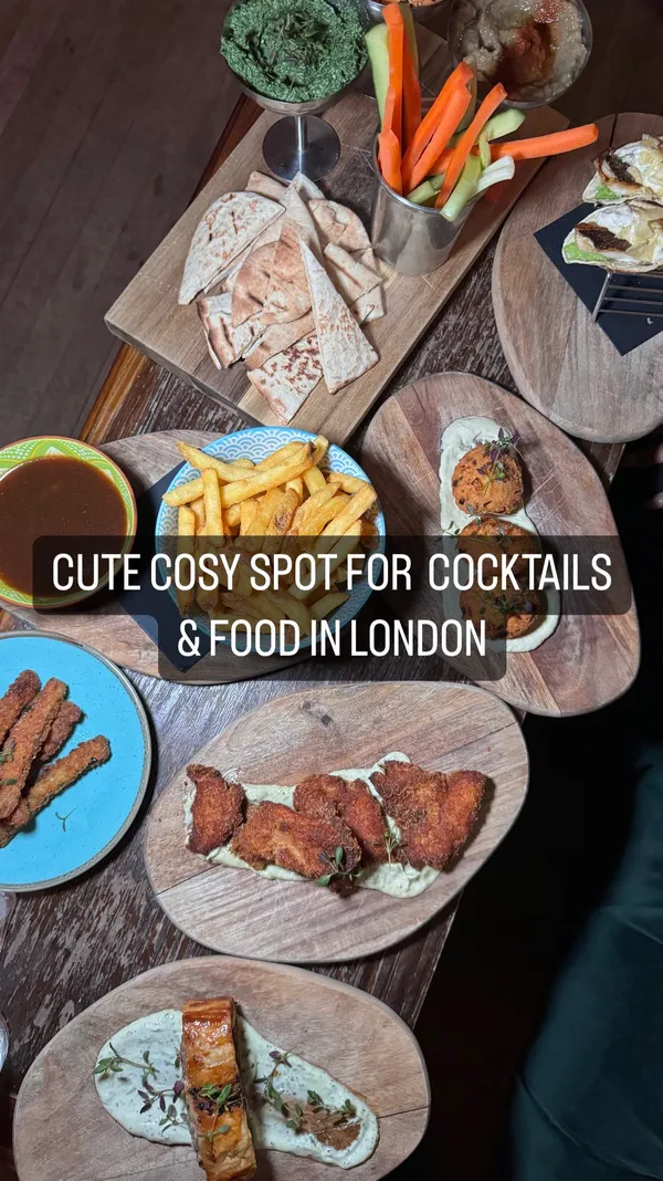 This video showcases The Little Blue Door in Fulham, London, highlighting its unique atmosphere and menu.  The video opens with a vibrant entrance, then shows various areas of the venue: a game room, snooker room, and laundry room. The food and drink focus is on tapas-style dishes and cocktails.  Specific items shown include mezze dips, sea bream tacos, sweetcorn fritters, a sausage roll, fries, zucchini fries, and chicken wings. The presentation emphasizes a cozy, intimate atmosphere. Dietary information is limited, but vegetarian options are mentioned. 