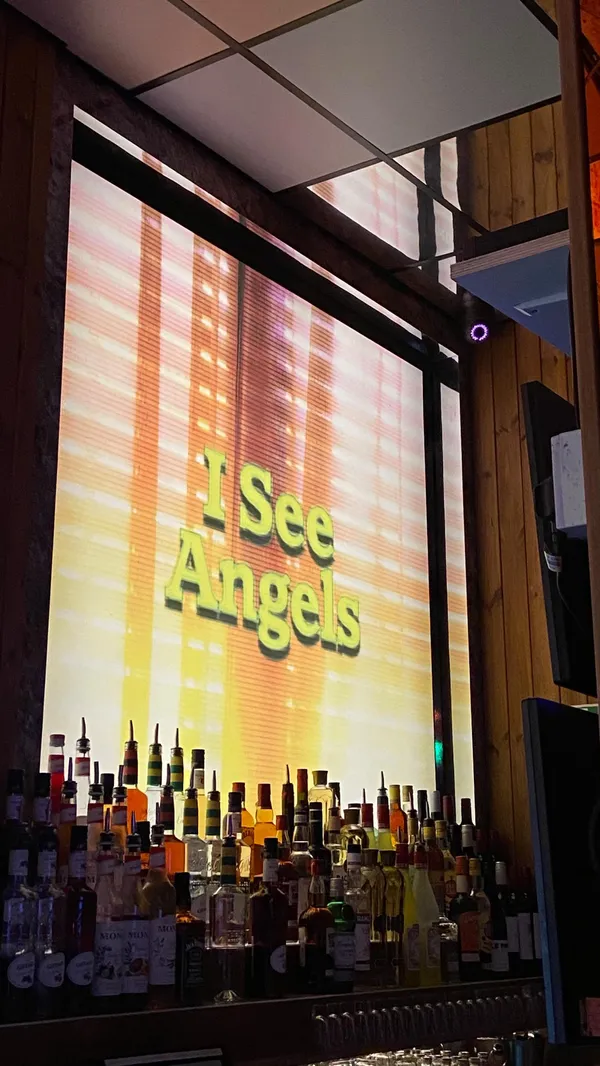 The video showcases Nikki's bar, a quirky cocktail spot in Shoreditch, London.  It highlights the bar's neon interior, photo booth, and cocktails. The cocktails shown include a pink foamy drink, a yellow drink with chili garnish, and a passion fruit-based cocktail that is flambéed. The video emphasizes the bar's fun and vibrant atmosphere.