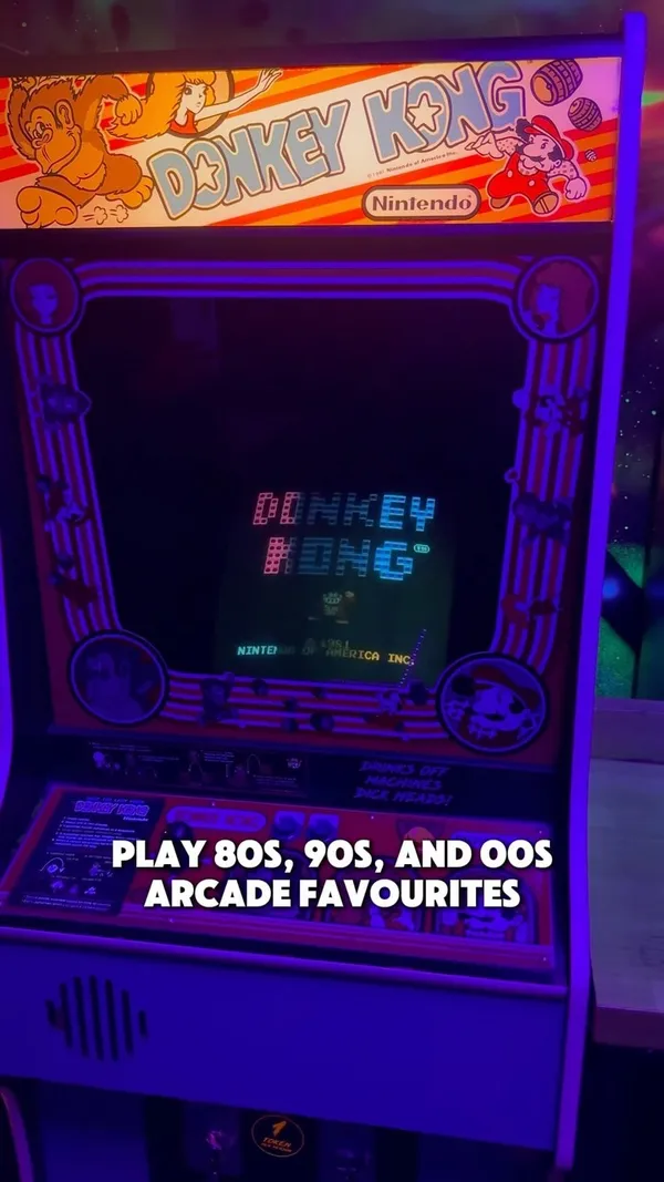 The video showcases NQ64, a neon-lit arcade bar in London. It features a variety of 80s, 90s, and 00s arcade games, including Pac-Man, Mario Kart, and Donkey Kong.  The bar also offers game-themed cocktails, such as the Kong Island Iced Tea, and retro music. The video highlights the energetic atmosphere and nostalgic experience of the venue, focusing on the fun of playing arcade games and enjoying themed cocktails with friends.
