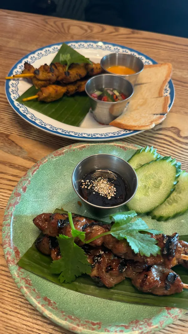 The video showcases a meal at Rosa's Thai restaurant in Westfield White City. It features various dishes including chicken gai satay, moo ping pork skewers, khao mun gai chicken & rice, king prawn pad thai, and churros.  The food is presented attractively on plates with garnishes.  No specific dietary information is provided. The main focus is on enjoying the meal and highlighting the food's deliciousness.
