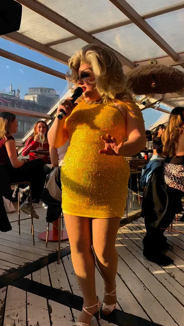 The video showcases a Mamma Mia-themed party at a rooftop bar in London. It features West End stars performing live, bottomless prosecco, wine, and cocktails (Aperol Spritz, Rum Punch, and Pornstar Martini), and a two-course meal (pita bread with various toppings and fries). The food is presented on white plates, while drinks are shown in glasses and jugs. No specific dietary information is mentioned. The main focus is the party atmosphere, with interspersed food and drink shots.
