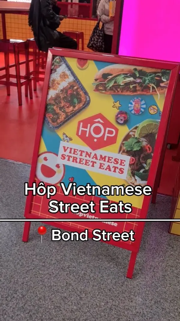 The video showcases HÔP Vietnamese Street Eats, a takeaway restaurant located in Bond Street Station. It features various dishes, including fried chicken, dumplings, rice bowls with different protein options, and bubble tea. The food is presented in vibrant, branded packaging and visually appealing settings.  Dietary information isn't explicitly mentioned, but several options seem to cater to different tastes. The video's primary focus is to highlight the food's taste and the restaurant's atmosphere.